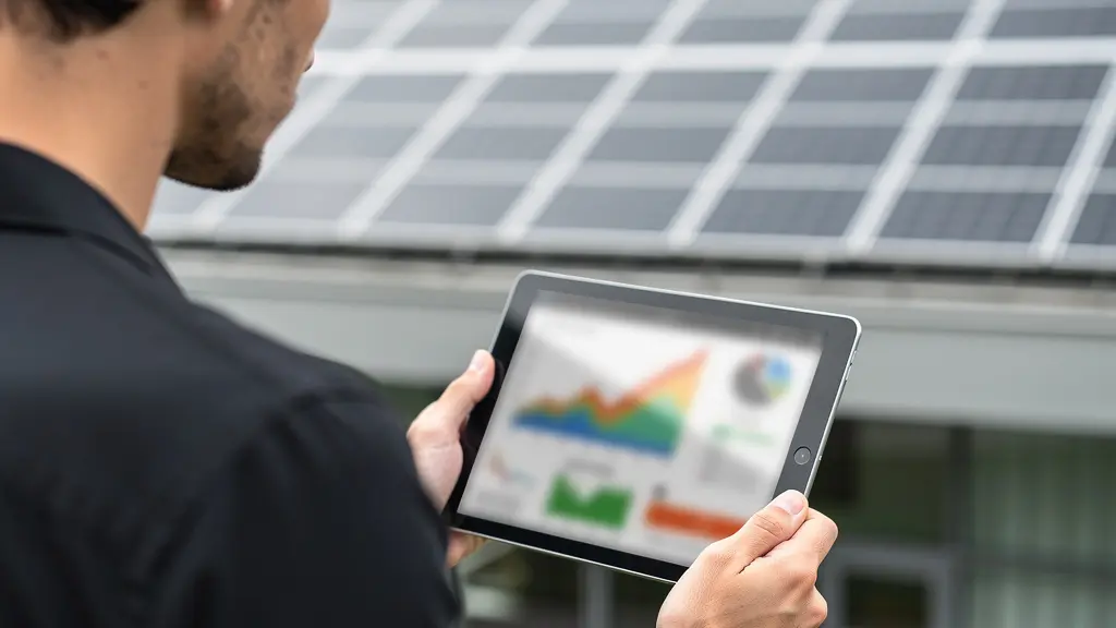 Conseiller photovoltaïque consultant des données de production sur tablette devant installation solaire